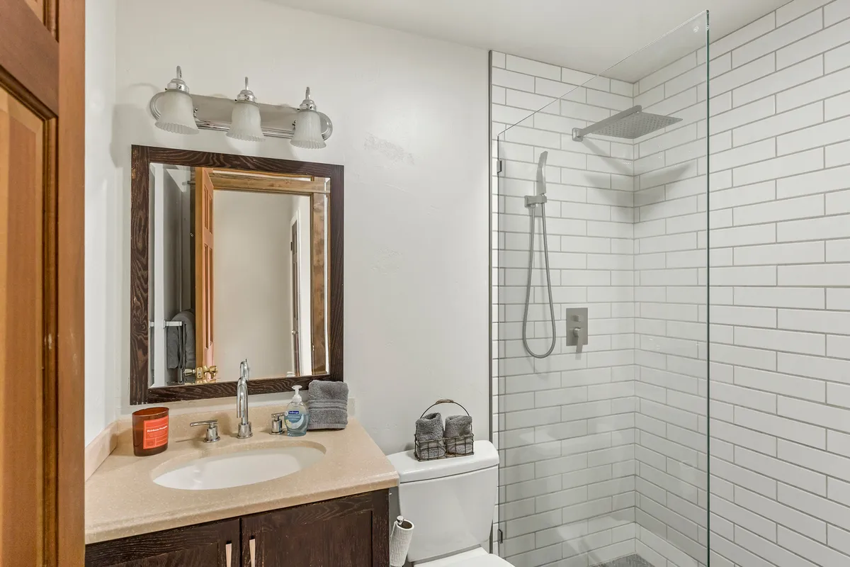 A bright and tranquil bathroom featuring a spacious vanity with a large mirror, a modern shower area, and a clean toilet. The scene is inviting, suggesting a refreshing environment ideal for unwinding and daily routines.