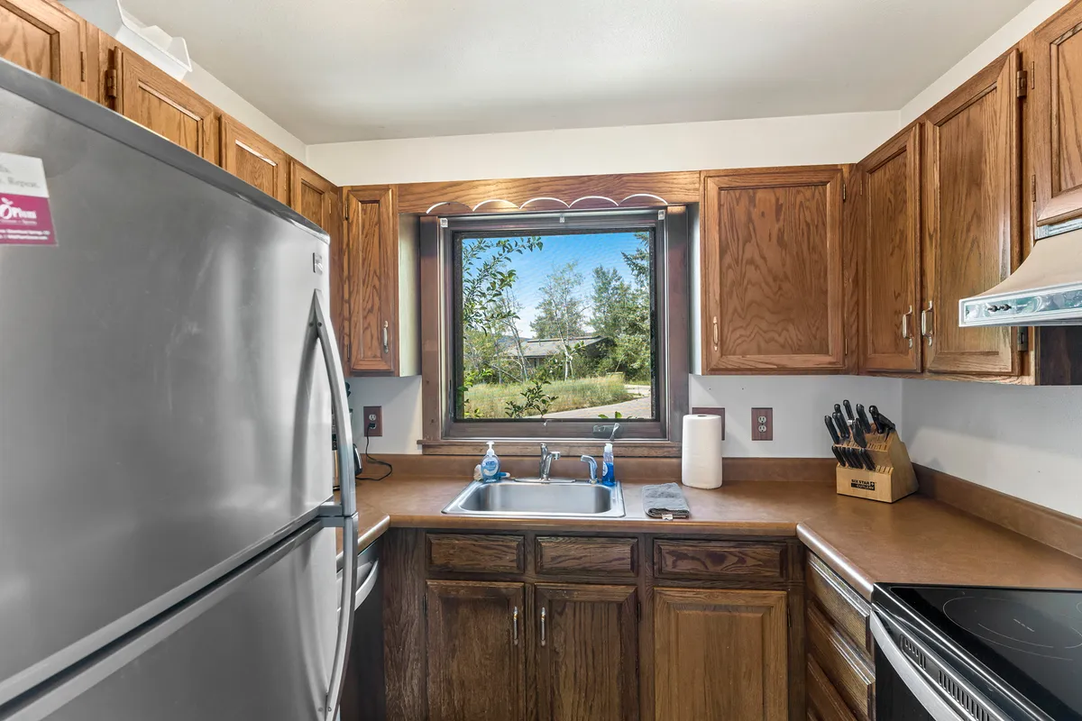 This image features a warm, homely kitchen space with a sink, window, kitchen cabinets, and countertop. The layout is open and inviting, perfectly suited for meal preparation and socializing. Soft lighting and thoughtful details set a welcoming tone for family gatherings or friendly conversations during meal prep.