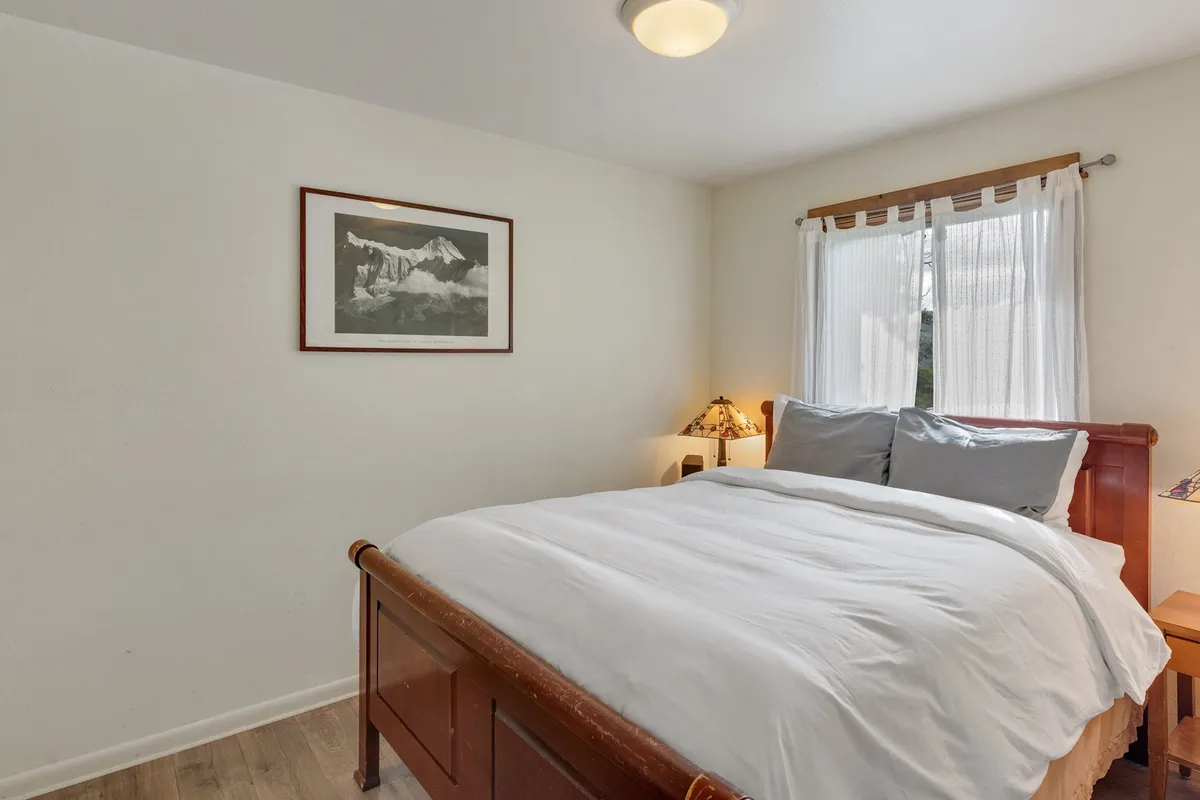 A cozy bedroom with a comfortable bed, soft natural light filtering through the window, tasteful artwork, and calming decor. The space exudes a sense of tranquility and privacy, ideal for restful nights or quiet moments.